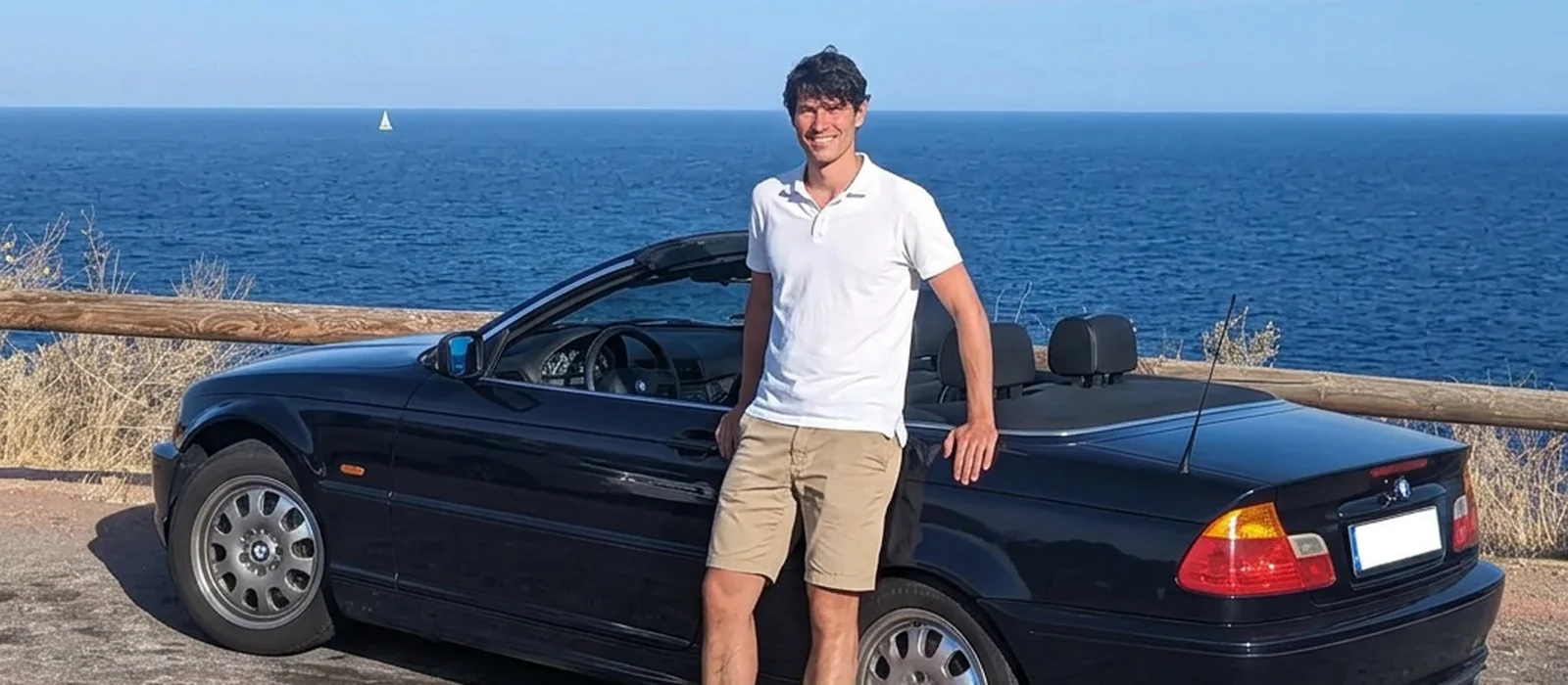 Radko Albrecht standing beside his dark blue BMW E46 convertible on the coast